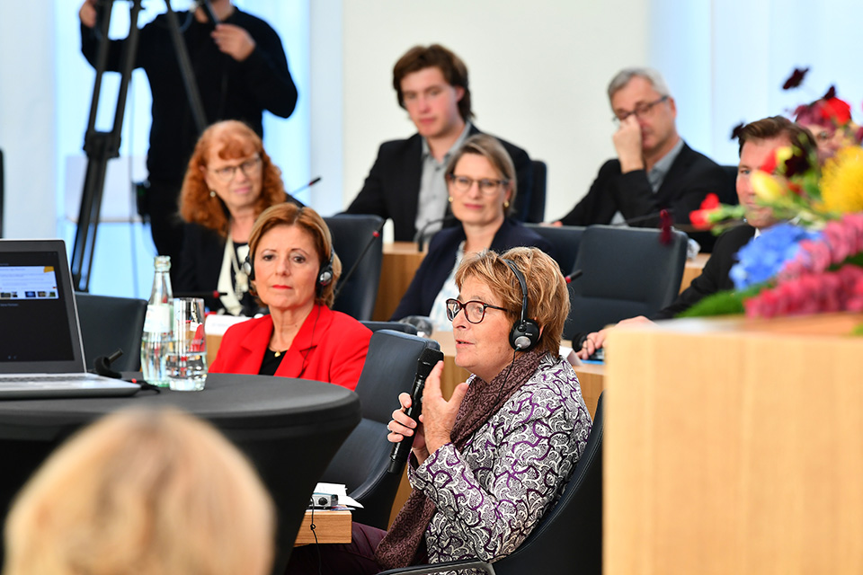 Das Gespräch findet im Plenarsaal des Deutschhauses statt. Alle Beteiligten tragen Kopfhörer für eine simultane Übersetzung.