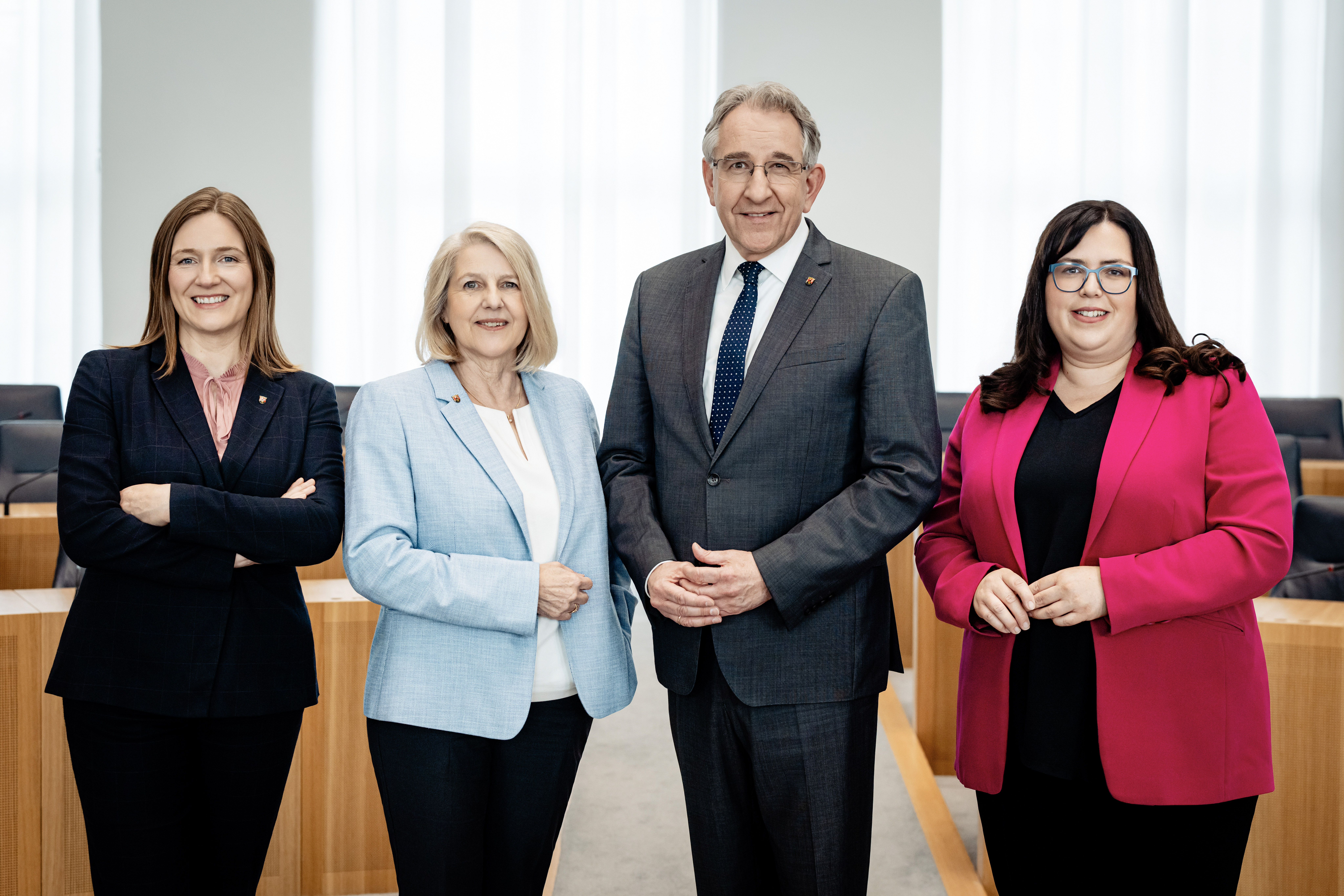 Zu sehen sind vier Personen nebeneinanderstehend im Rund des Plenarsaals.