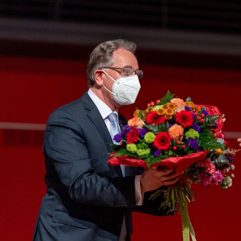 Er übergibt an eine Abgeordnete einen Blumenstrauß