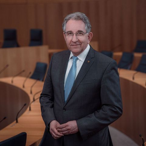 Der Vizepräsident des Landtags Rheinland-Pfalz, Matthias Lammert. Das Foto ist horizontal ausgerichtet. Der Vizepräsident steht lächelnd zwischen den Stuhlreihen des Plenarsaals.
