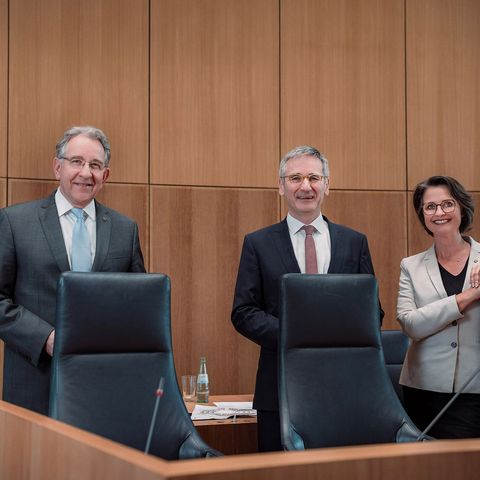 Die Mitglieder des Vorstands stehen lachend hinter den Sitzen des Sitzungsvorstands im Plenarsaal des Deutschhauses.