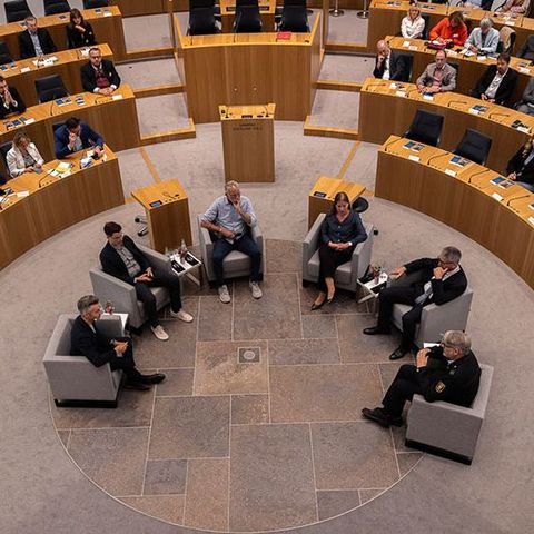 Das Bild zeigt von der Tribüne aus die Gäste der Talk-Runde im Plenarsaal. Blick von oben in das Plenarrund.