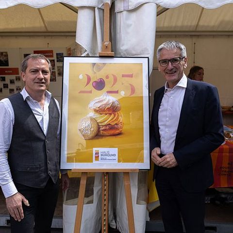 Landtagspräsident Hendrik Hering steht mit einer weiteren Person vor dem Stand. Zwischen ihnen befindet sich das gerahmte Plakat zum 30jährigen Bestehen des Hauses Burgund.
