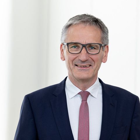 Landtagspräsident Hendrik Hering lächelt. Er steht vor einem Fenster. das Bild wirkt hell und licht.