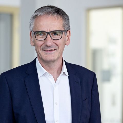 Landtagspräsident Hendrik Hering lächelt. Er steht vor einem Fenster. Das Bild wirkt hell und licht.