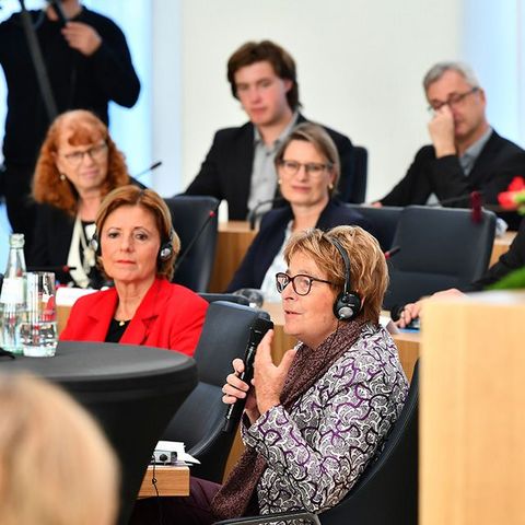 Das Gespräch findet im Plenarsaal des Deutschhauses statt. Alle Beteiligten tragen Kopfhörer für eine simultane Übersetzung.