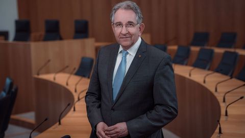 Der Vizepräsident des Landtags Rheinland-Pfalz, Matthias Lammert. Das Foto ist horizontal ausgerichtet. Der Vizepräsident steht lächelnd zwischen den Stuhlreihen des Plenarsaals.