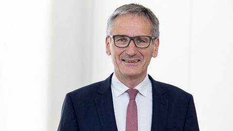 Landtagspräsident Hendrik Hering lächelt. Er steht vor einem Fenster. das Bild wirkt hell und licht.
