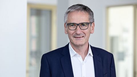 Landtagspräsident Hendrik Hering lächelt. Er steht vor einem Fenster. Das Bild wirkt hell und licht.