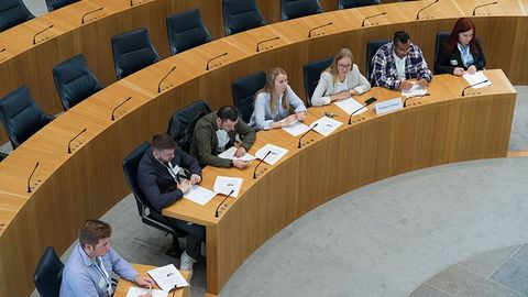 Die Teilnehmenden sitzen während den Debatten auf den Stühlen der Abgeordneten im Plenarsaal (Vogelperspektive).