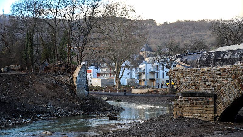 Eine völlig zerstörte Brücke an der Ahr; im Hintergrund die Ortschaft