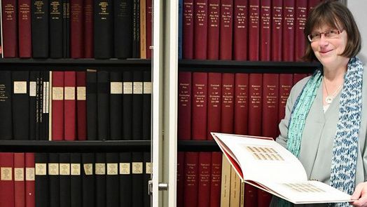 Mitarbeiterin des Archivs befindet sich vor einem großen Aktenschrank.