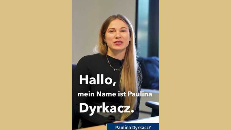Zu sehen ist eine Frau. Sie hat lange Haare und tr&auml;gt einen schwarzen Pullover. Sie schaut l&auml;chelnd in die Kamera. Auf dem Foto steht mit wei&szlig;er Schrift: "Hallo, mein name ist Paulina Dyrkacz". Das Foto wurde mittig auf eine gelbe Farbfl&auml;che platziert.