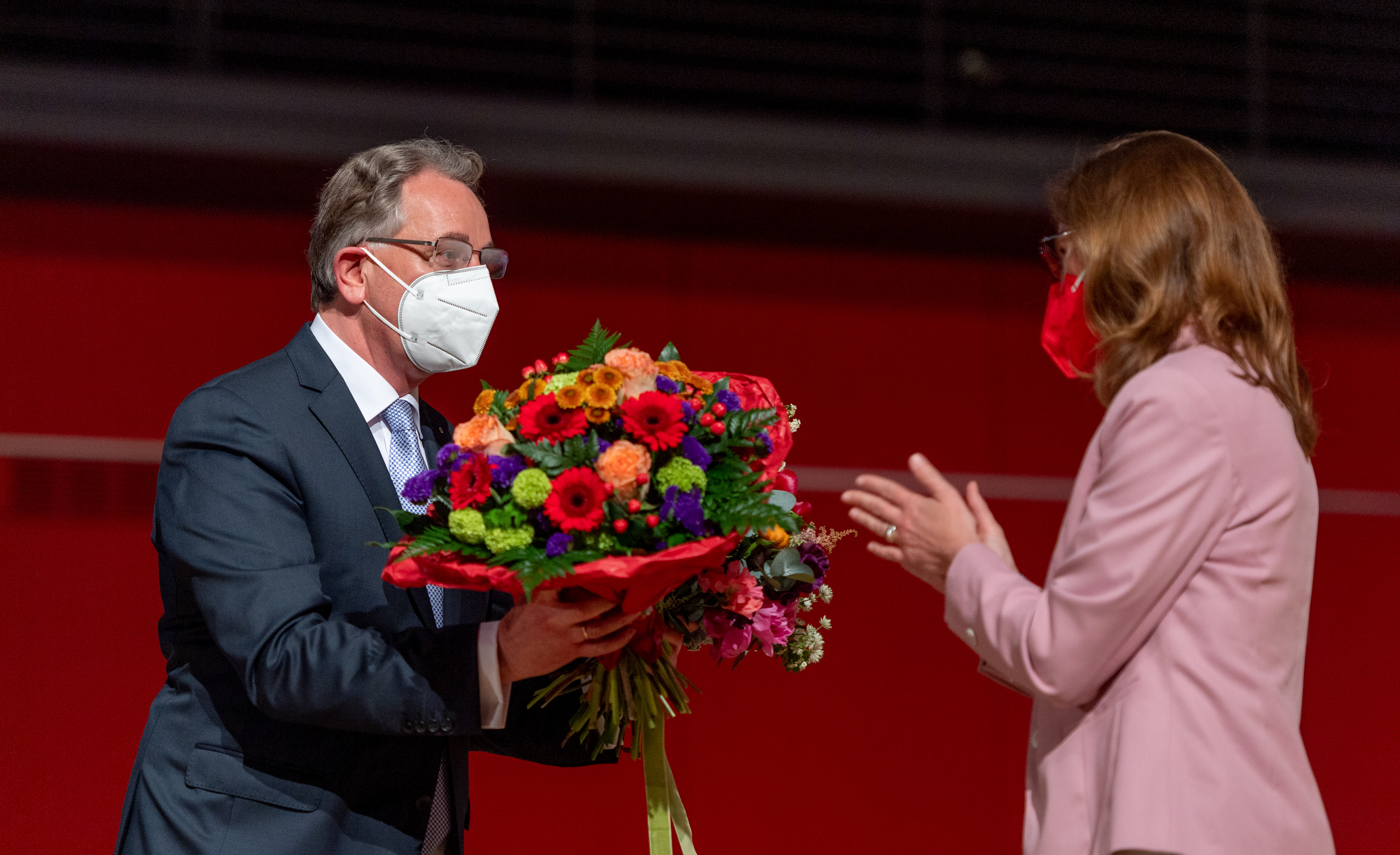 Er übergibt an eine Abgeordnete einen Blumenstrauß