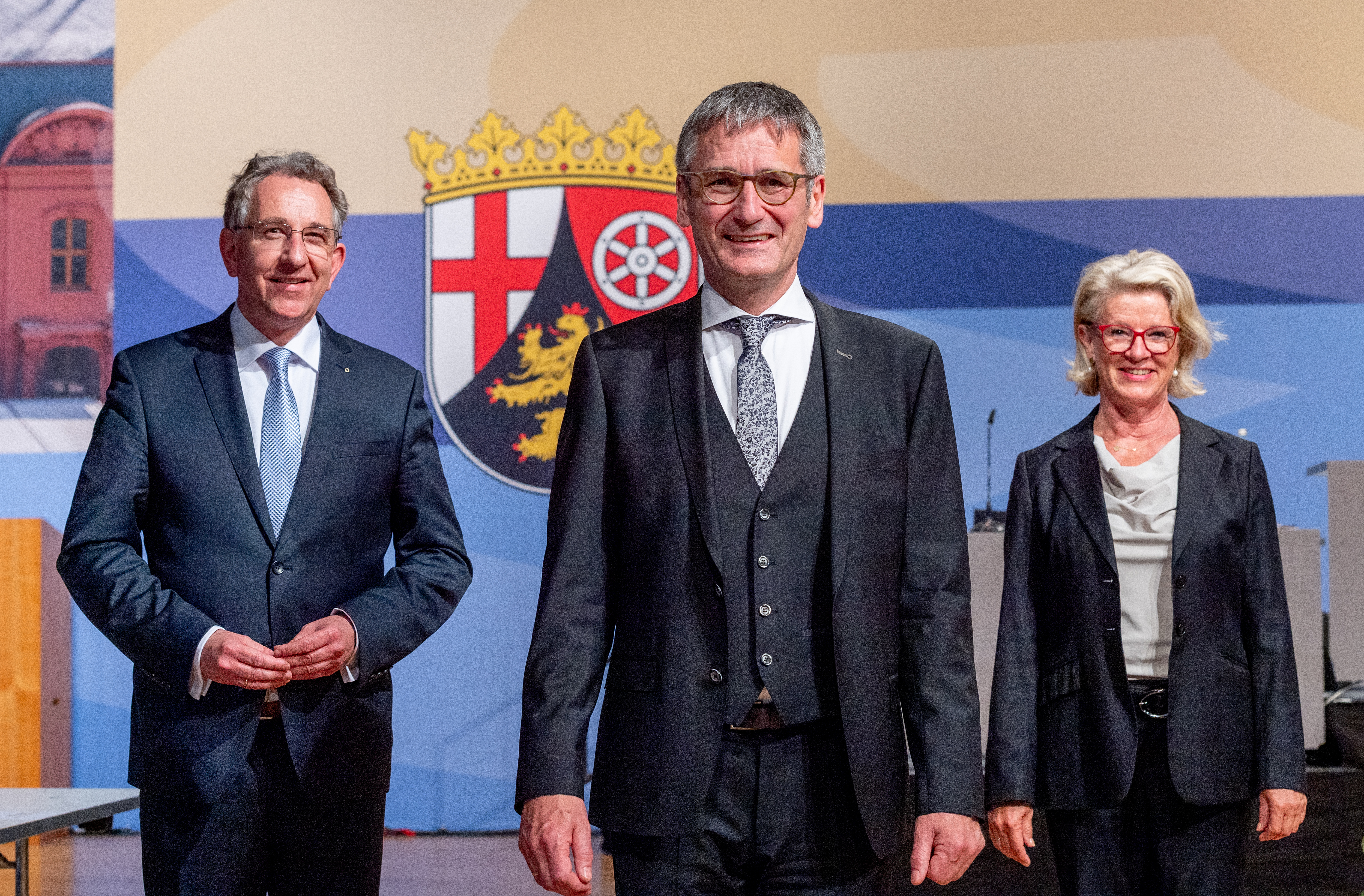 Die drei hochrangigen Politiker stehen vor dem Landeswappen des Landes Rheinland-Pfalz.