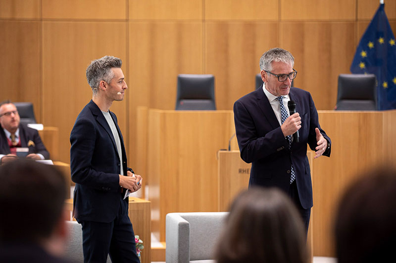 Landtagspräsident Hendrik Hering spricht in das Mikrofon. Marvin Neumann steht neben ihm.