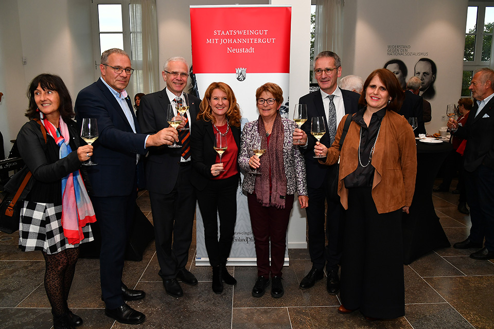 Gruppenbild im Foyer des Plenarsaals vor einem Aufsteller des Staatsweinguts mit Johannitergut Neustadt.
