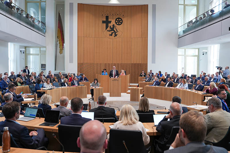 Ausschnitt aus einer Plenarsitzung. Der Ministerpräsident steht hinter dem Pult. Im Plenarsaal sitzen vielen Menschen.