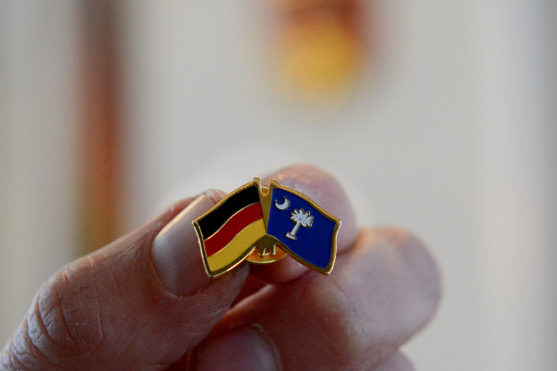 Transatlantische Konferenz 2015; Anstecknadel mit der deutschen Flagge und der Flagge es Staates South Carolina in der Hand eines Konferenzteilnehmers