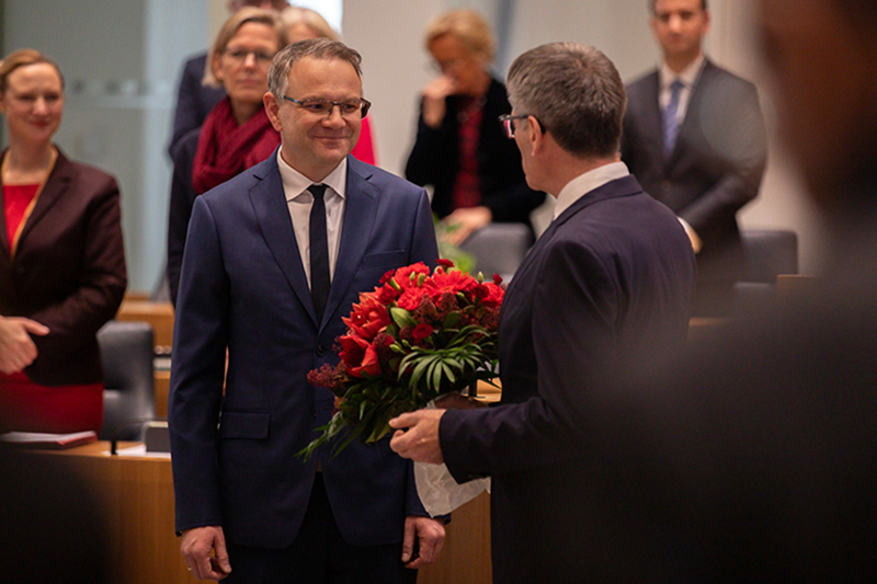 Ein Foto vom Landtags-Pr&auml;sident Hendrik Hering und Martin Haller. Hendrik Hering gibt Martin Haller einen Blumen-Strau&szlig;.