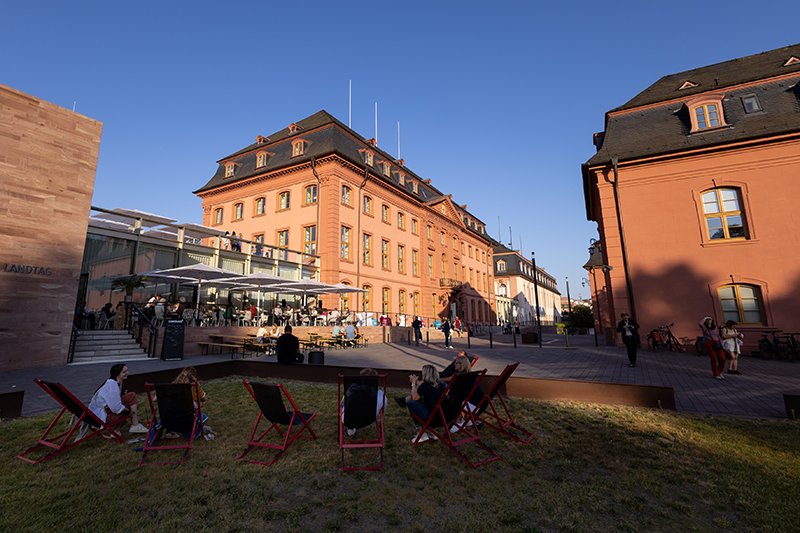 Zu sehen sind die Gebäude teils in der Sonne und teils im Schatten, der untergehenden Sonne.