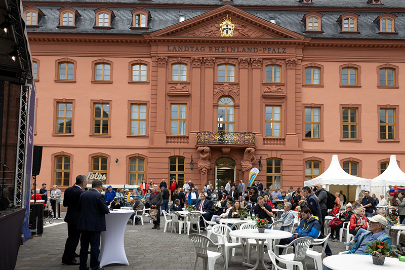 Viele Gäste sitzen im Hof vor dem Deutschhaus und hören der Eröffnungsrede von Hendrik Hering zu.